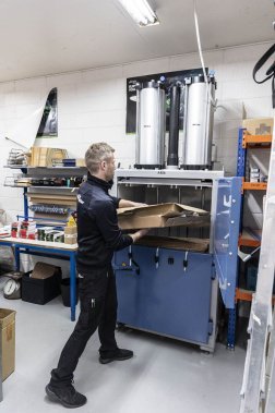 mecánico introduciendo cartón en una prensa de balas en el taller